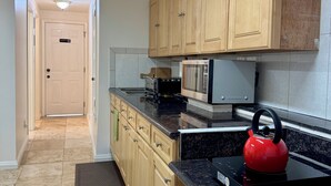 A kitchen with wooden cabinets, a microwave, a kettle, and a black countertop. - Cozy Inner Richmond Apartment, Steps to Golden Gate Park (San Francisco)