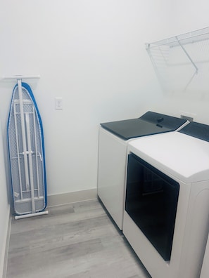 Un cuarto de lavandería con un tendedero, una lavadora y una secadora.