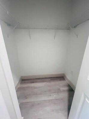 Een kamer met een houten vloer, witte wanden en een plafond met zichtbare balken.