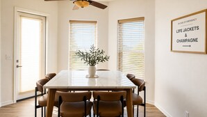 A dining room with a marble table, six chairs, a ceiling fan, and a potted plant. - Desert Retreat / Brand new interior / Pool / Views (Bullhead City)