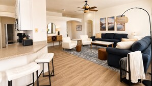 A modern living room with a sofa, chairs, a coffee table, and a kitchen area with a refrigerator and toaster. - Desert Retreat / Brand new interior / Pool / Views (Bullhead City)