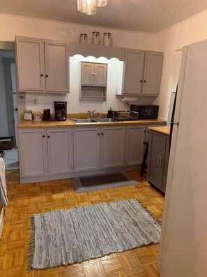 A compact kitchen with grey cabinets, a microwave, and a coffee maker. - NEW Listing Half Block to Downtown Treetop Apt 3bd (Black Mountain)