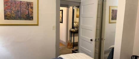 Un dormitorio con una cama, una puerta que da al baño y un cuadro en la pared.