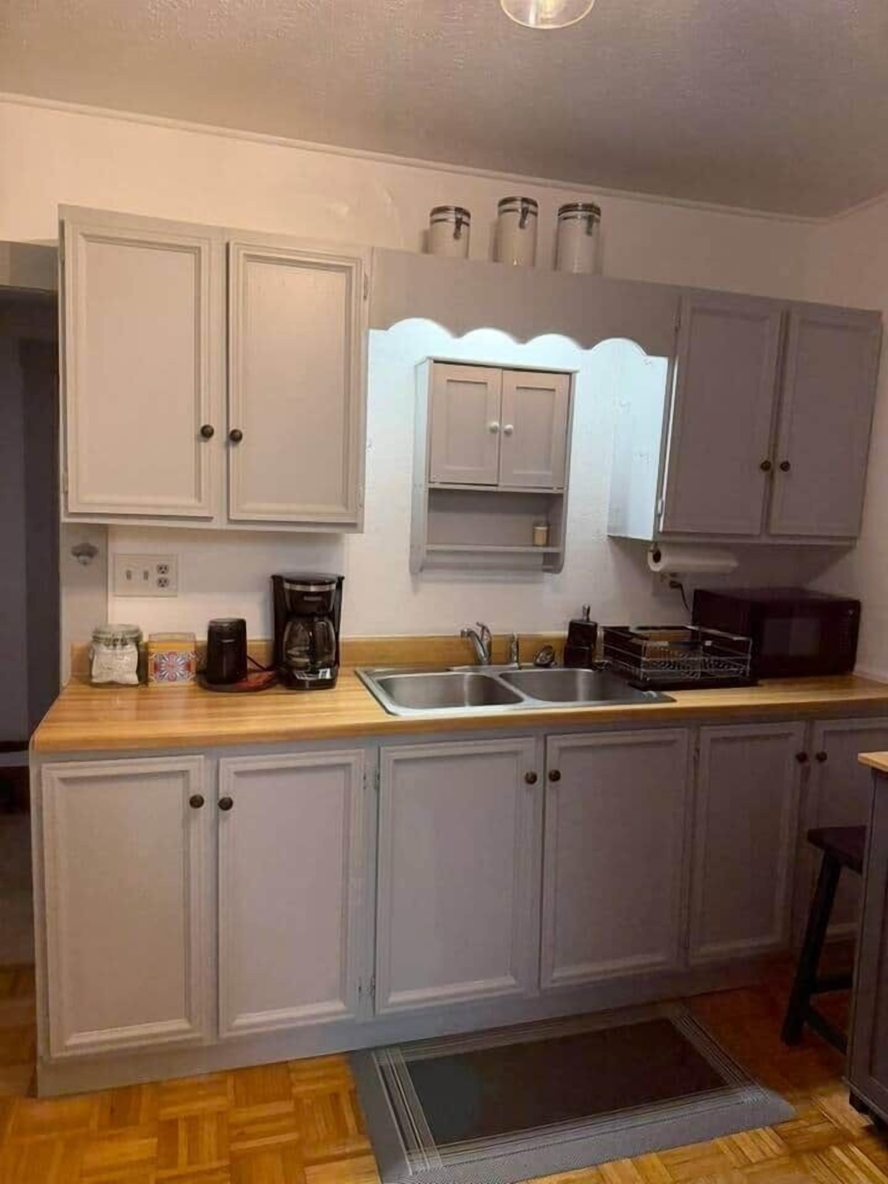A compact kitchen with a wooden countertop, a sink, and cabinets.