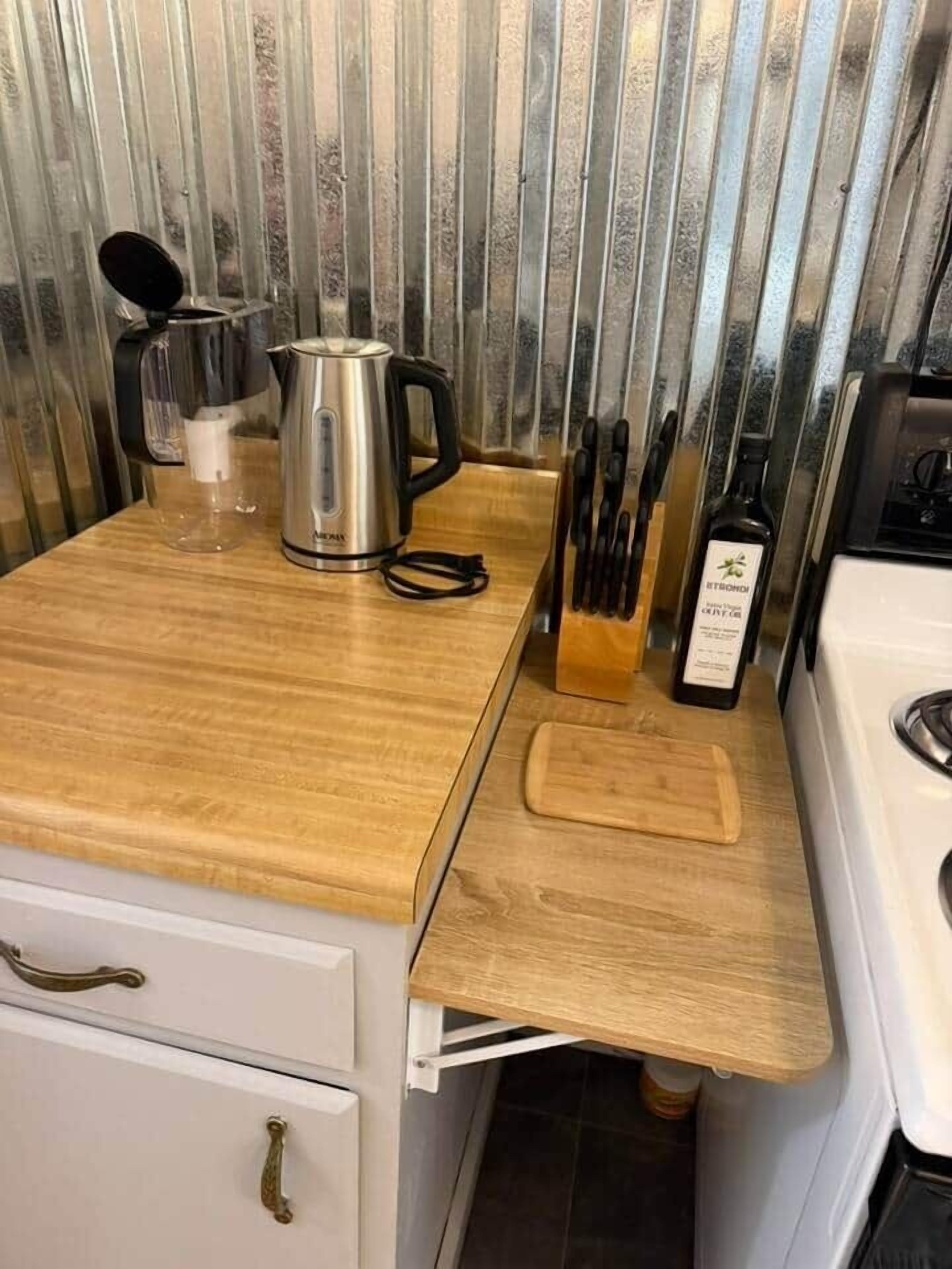 A kitchen with a wooden countertop, a stainless steel kettle, a knife block, and a bottle of olive oil.