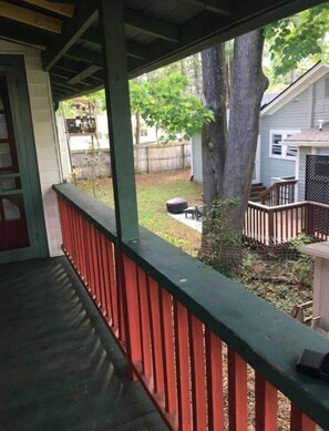 A covered porch with a red railing, a tree in the background, and a fenced yard. - NEW Listing Half Block to Downtown Treetop Apt 3bd (Black Mountain)