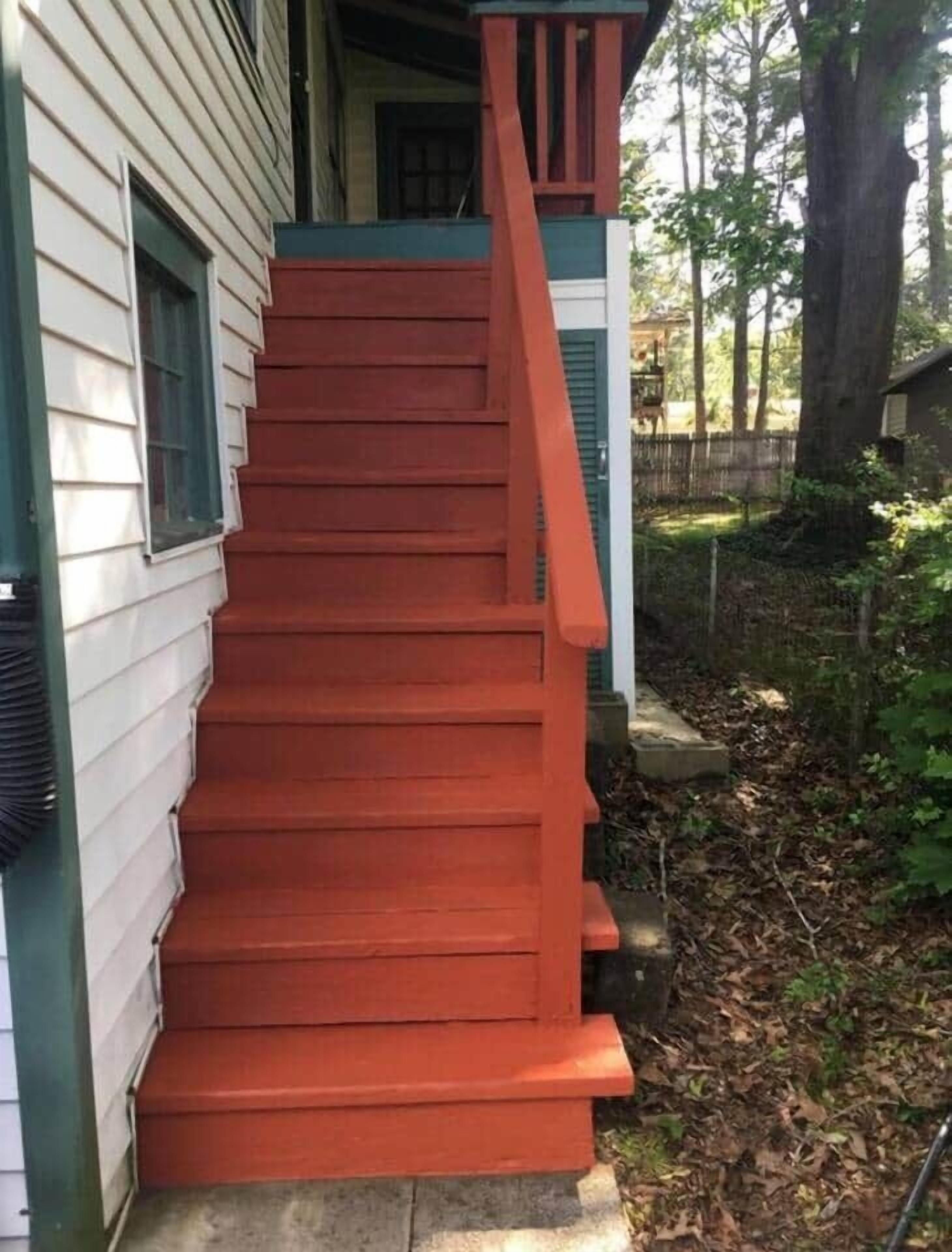 Una scala di legno che porta a una casa con una porta verde e finestre.