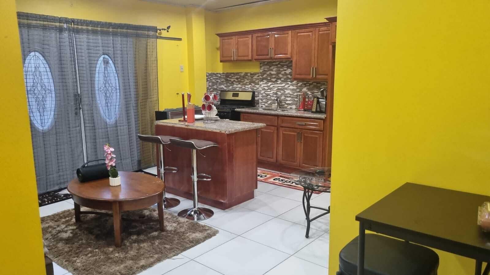 A compact kitchen with wooden cabinets, a central island, and a dining area with a table and chairs.
