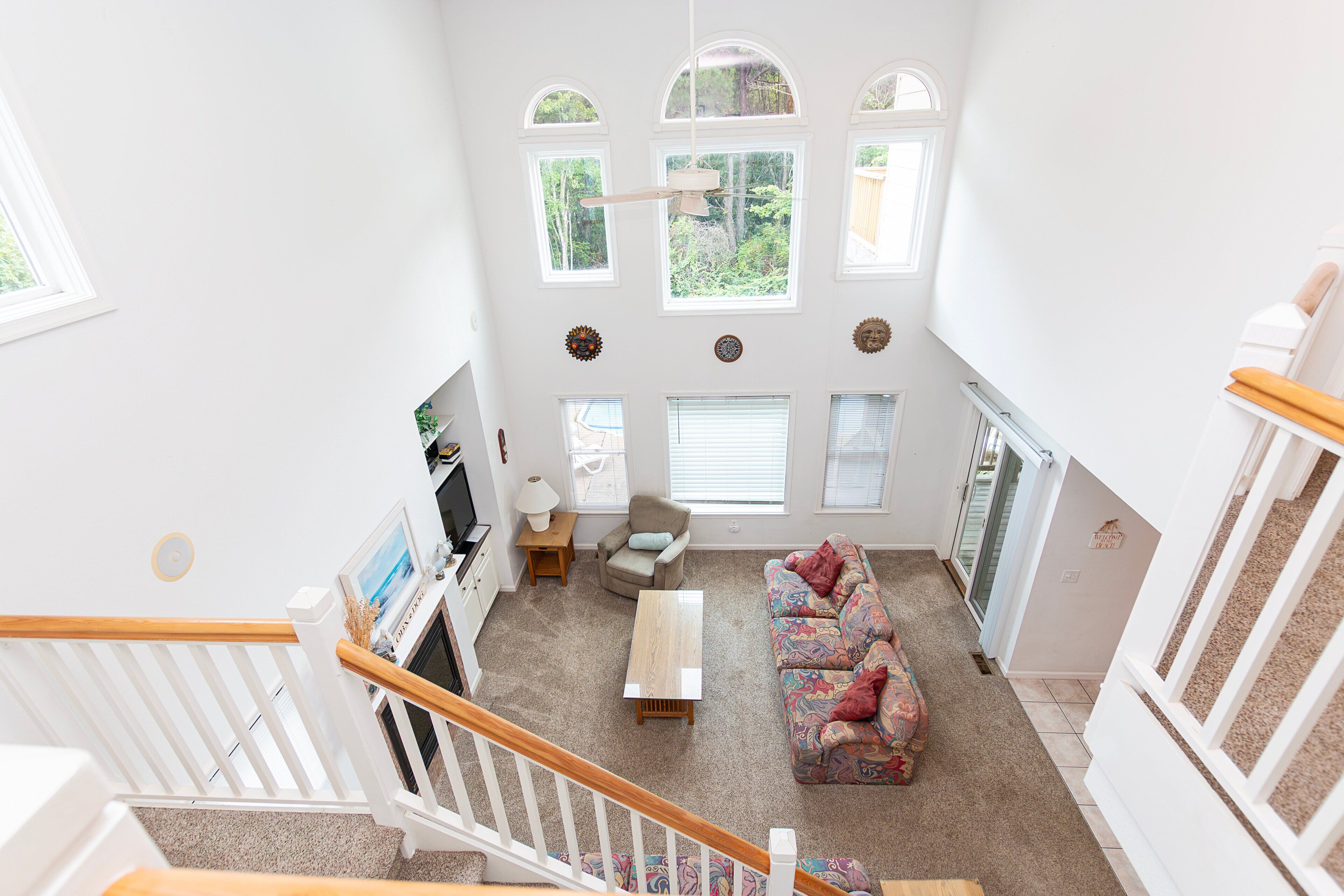 A spacious living area with a sofa, a television, and a staircase leading to an upper floor.