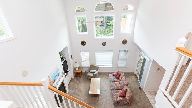 A spacious living area with a sofa, a television, and a staircase leading to an upper floor. - Soundside- Golf Community, Priv Pool, Htub-MB3, How Sweet the Sound (Corolla)