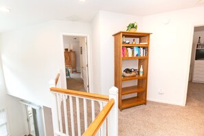 Ein Zimmer mit einer Holzbücherwand, Teppichboden und einer weißen Tür zu einem weiteren Raum.