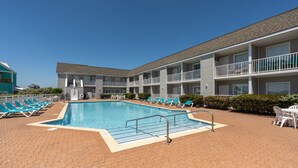 Ett hotell med en swimmingpool, flera balkonger och solstolar.