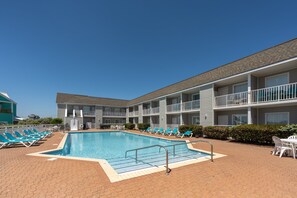 Ein Hotel mit Schwimmbad, mehreren Balkonen und Liegestühlen.