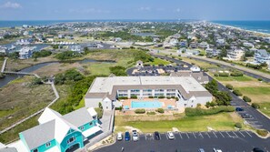 A large building with a swimming pool, surrounded by parking and a road. - Cozy Condo with Private Patio & Pool Access in Hatteras Village-  HIH212, Captain's Quarters (Hatteras)