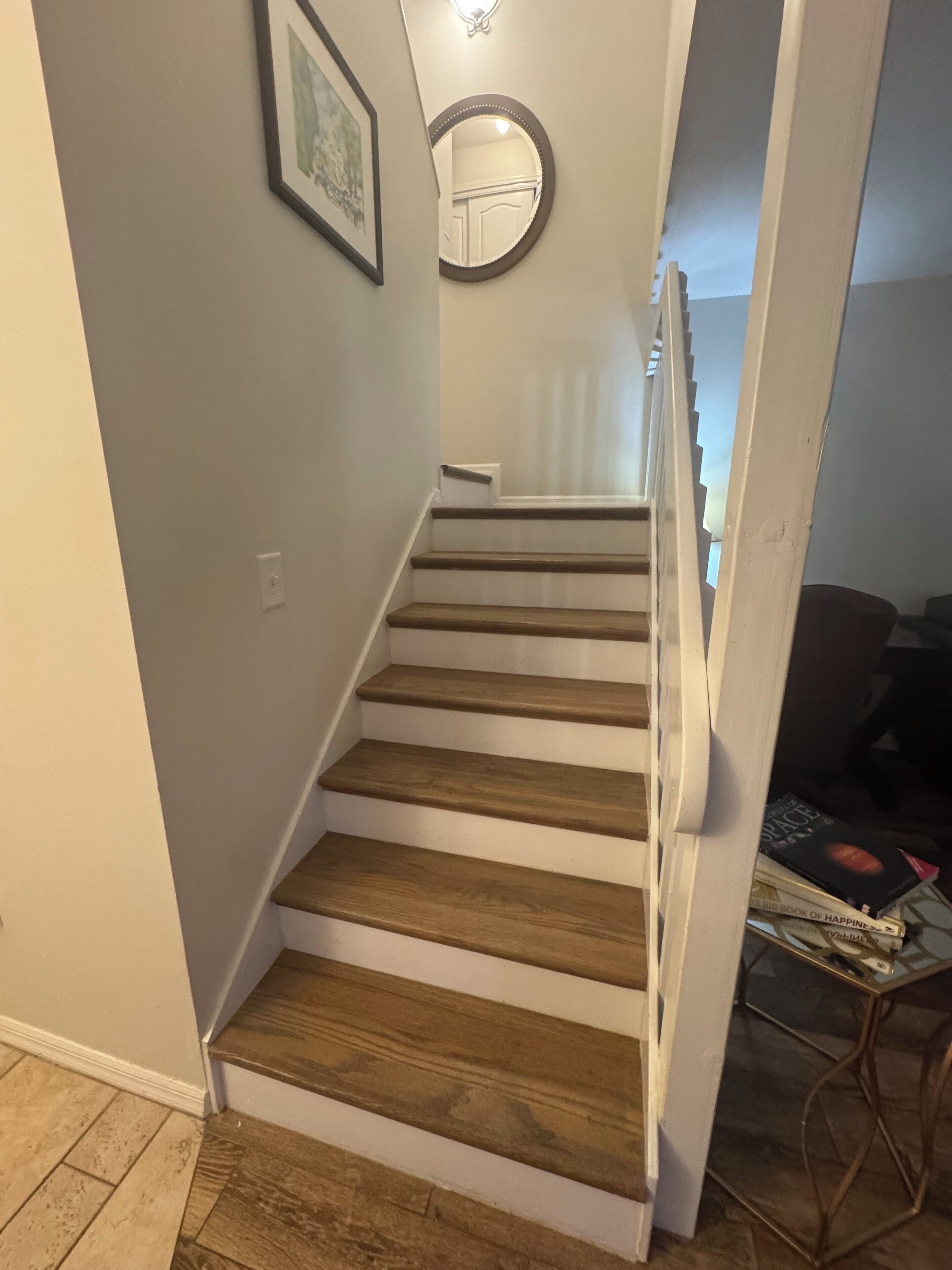 A staircase with wooden steps and white railings, leading to an upper floor.