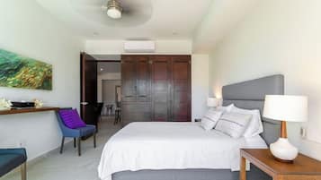 A modern bedroom with a bed, bedside table, chair, and artwork on the wall.