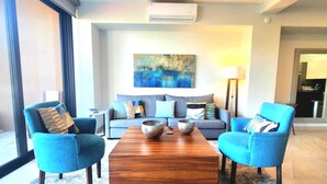 Una sala de estar moderna con un sofá, dos sillones, una mesa de centro y un cuadro en la pared.
