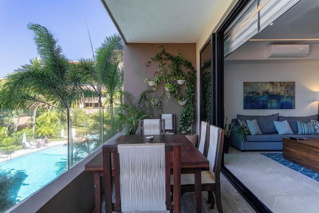 Un balcón con una mesa de comedor, sillas y vistas a una piscina.