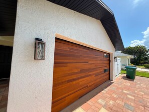 A modern garage with a large wooden door, a textured wall, and a small window. - 3-bedroom house in peaceful Cape Coral with heated saltwater pool (Cape Coral)