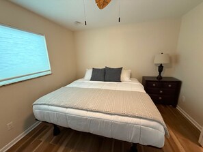A bedroom with a bed, a nightstand, a lamp, and a window with blinds. - 3-bedroom house in peaceful Cape Coral with heated saltwater pool (Cape Coral)