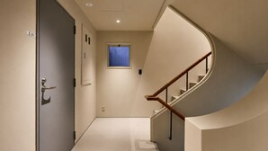 Um corredor com porta, janela e escadaria em curva.