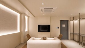 Quarto de hotel moderno com uma cama grande, televisão de tela plana na parede e um closet espaçoso.