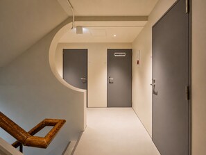 A hallway with two doors, one with a sign, and a wooden chair.