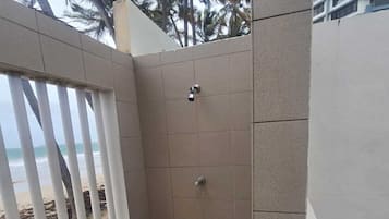 Un área de ducha pequeña y cerrada, con paredes de azulejos y un cabezal de ducha metálico.