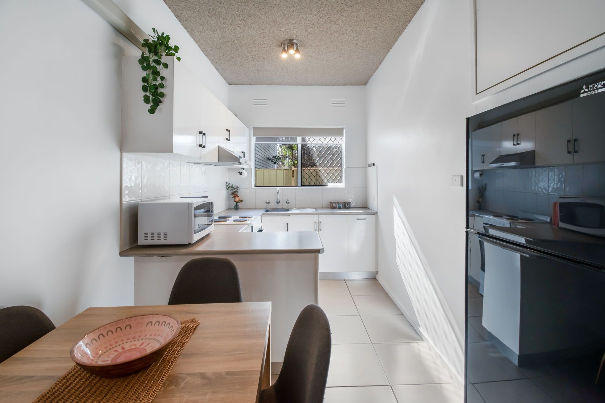 A modern kitchen with white cabinetry, a central island, and a dining area with a table and chairs.