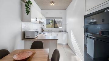 A modern kitchen with white cabinetry, a central island, and a dining area with a table and chairs.