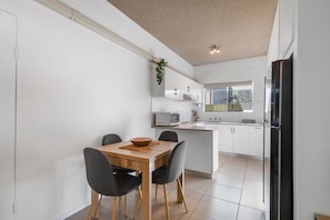 Une cuisine moderne avec des meubles blancs, un four à micro-ondes et un réfrigérateur noir.