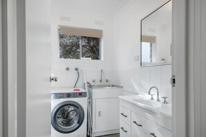 A modern bathroom with a washing machine, a sink, and a mirror. - Simmons Retreat, Wagga (Wagga Wagga)