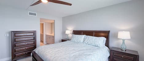 Een slaapkamer met een bed, nachtkastjes, een plafondventilator en een inloopkast.