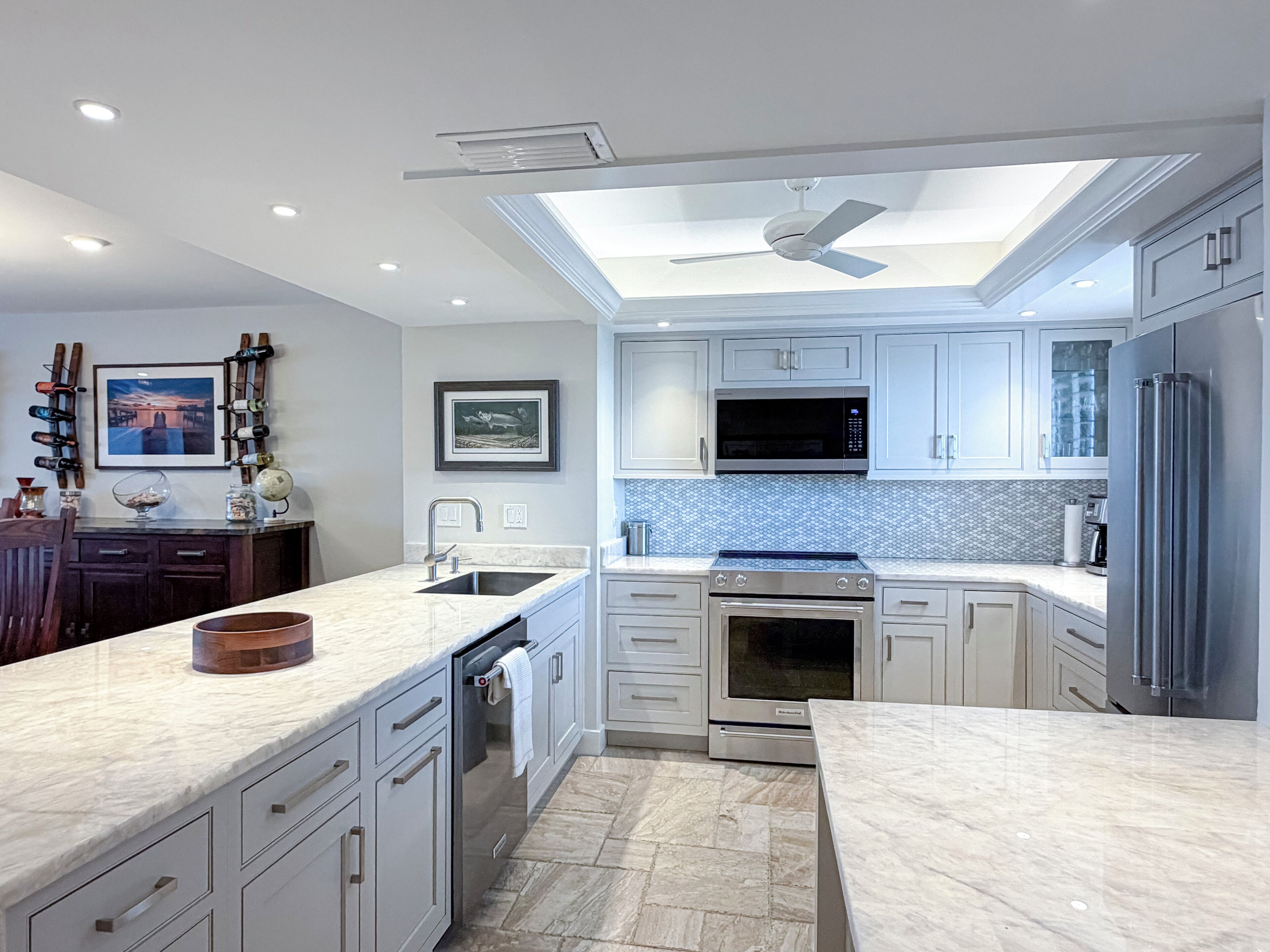 A modern kitchen with white cabinetry, a built-in oven, a microwave, and a stainless steel refrigerator.
