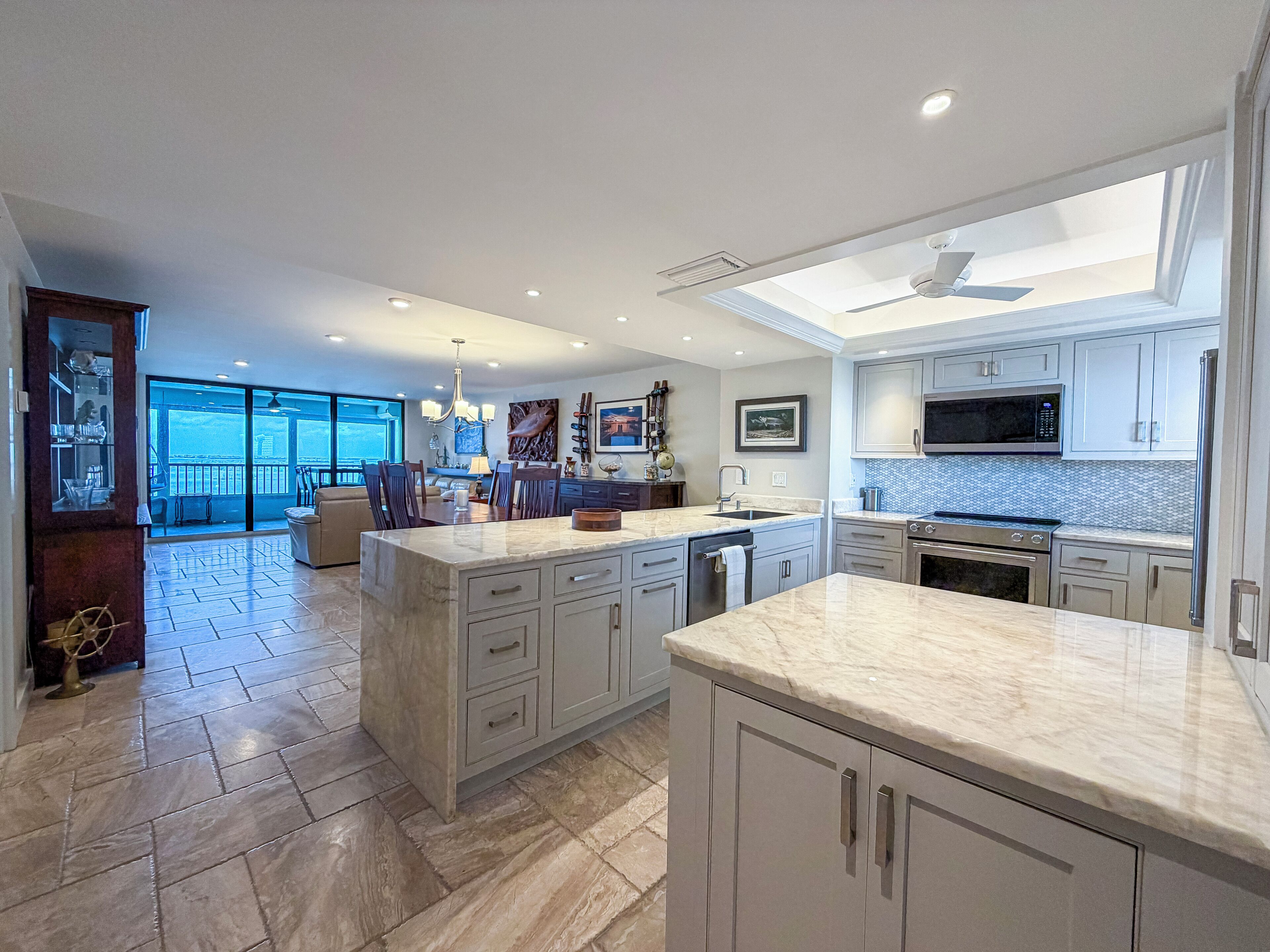 A modern kitchen with a large island, built-in appliances, and a view to a balcony.
