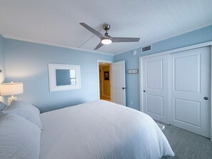 Ein Schlafzimmer mit einem Bett, einem Deckenventilator, einer Tür und einem Fenster.