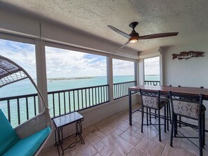 Ein Balkon mit Meerblick, ein Deckenventilator und ein Tisch mit Stühlen.
