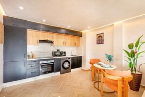 A compact kitchen with modern appliances, wooden cabinets, and a dining area with a table and chairs. - 1-bedroom apartment in tranquil Marrakech with AC (Marrakech)