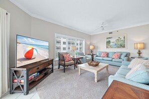 Ein Wohnzimmer mit Fernseher, einer Couch, einem Couchtisch und einem Sessel.