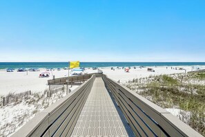 A boardwalk leading to a beach with umbrellas and beach chairs. - Gulf-Front Views | Spacious 3BR | Beach Access & Pool | BEACHBALL PROPERTIES (Orange Beach)