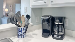 A kitchen counter with a utensil holder, a coffee maker, and a coffee pot. - Gulf-Front Views | Spacious 3BR | Beach Access & Pool | BEACHBALL PROPERTIES (Orange Beach)