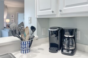 Eine Küchenarbeitsplatte mit einem Utensilienhalter, einer Kaffeemaschine und einer Kaffeekanne.