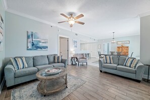 A living room with two grey sofas, a coffee table, and a ceiling fan. - Gulf-Front Views | Spacious 3BR | Beach Access & Pool | BEACHBALL PROPERTIES (Orange Beach)