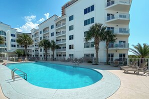 Ein Hotel mit Schwimmbad, mehreren Balkonen und Palmen.