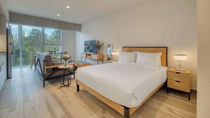 A modern hotel room with a large bed, a desk, and a view of the outdoors. - Providencia Deluxe Studio in Brand-New Building (Guadalajara)