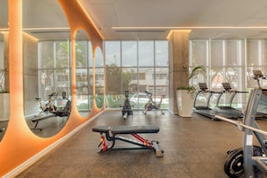 Ein Fitnessraum mit Trainingsgeräten, großen Fenstern und modernem Design.