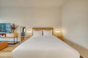 A hotel room with a large bed, bedside tables with lamps, a desk with a chair, and a view of the outdoors. - Providencia Deluxe Studio in Brand-New Building (Guadalajara)