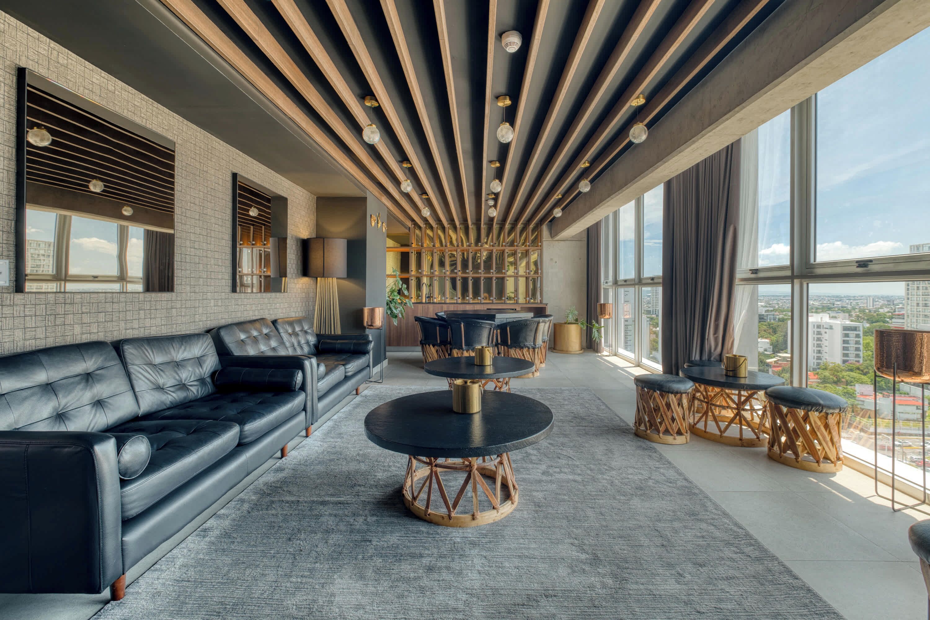 Ein stilvoller Lounge-Bereich mit Ledersofas, runden Tischen und Blick auf die Stadt.