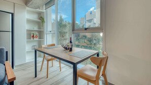 A modern kitchen with a dining table, chairs, and a large window with a city view. - Providencia Deluxe Studio in Brand-New Building (Guadalajara)