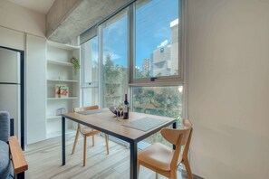 Eine moderne Küche mit Esstisch, Stühlen und einem großen Fenster mit Blick auf die Stadt.